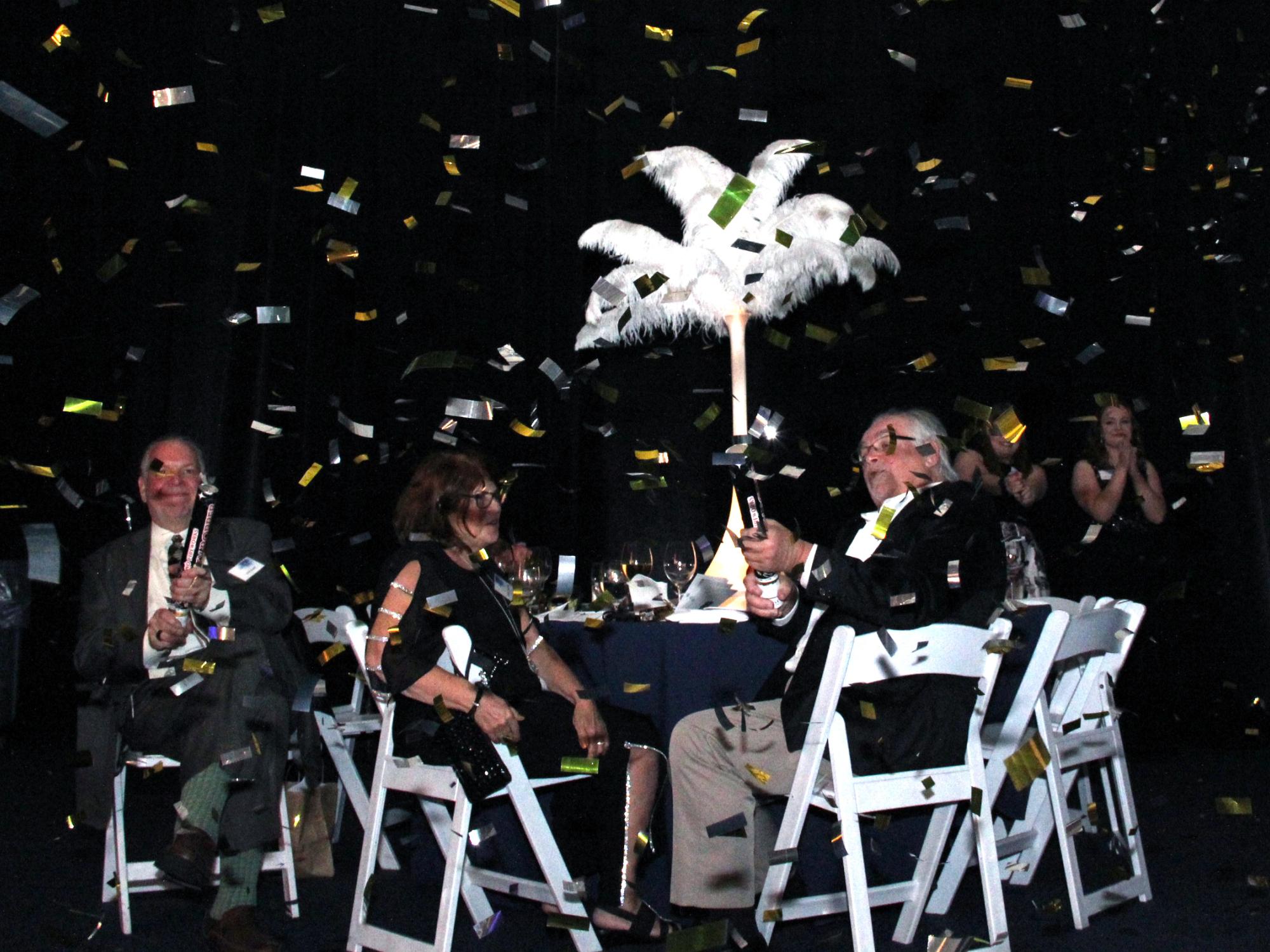 people sitting at a table with a confetti paper 