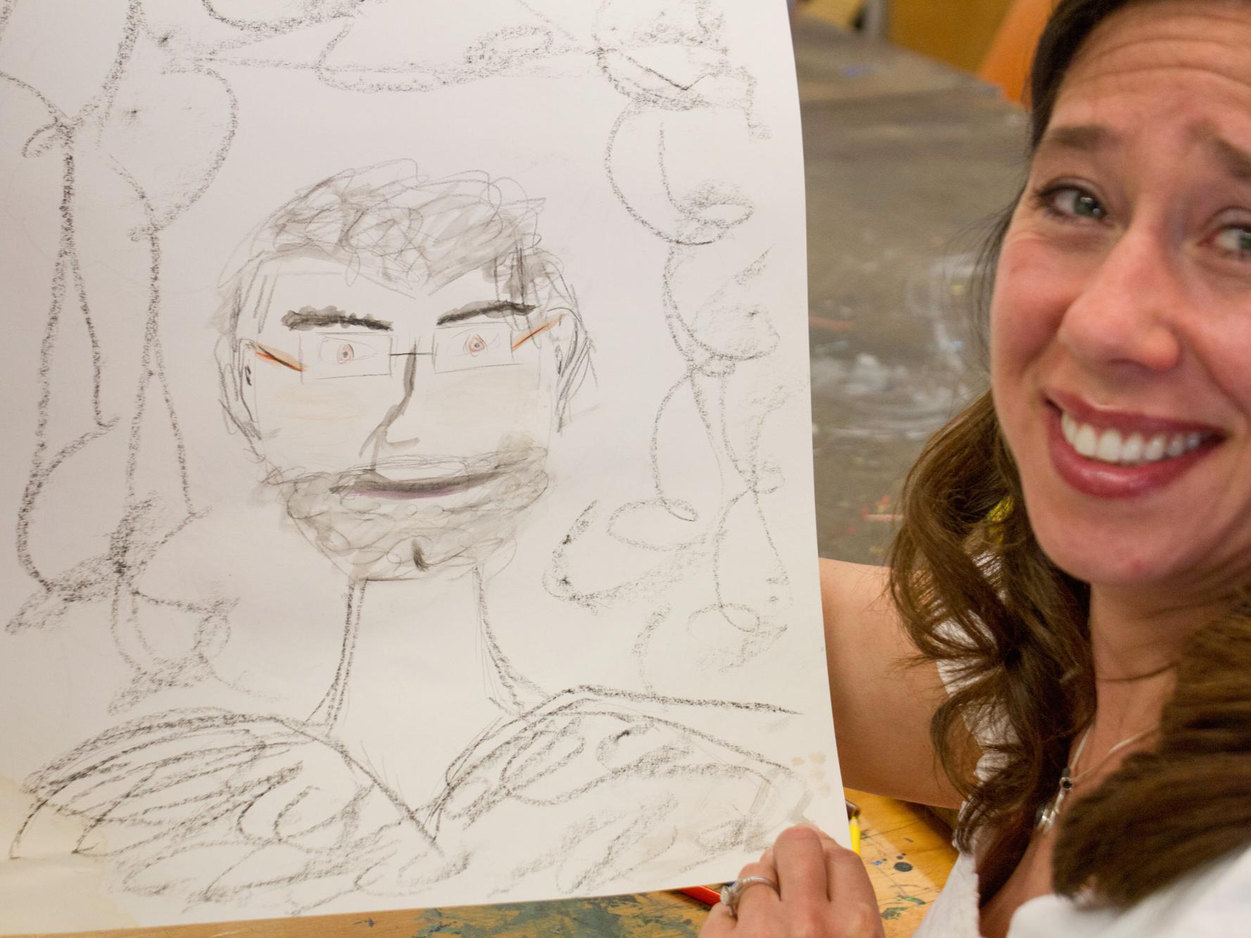 A staff member holds up a sketch she drew. 