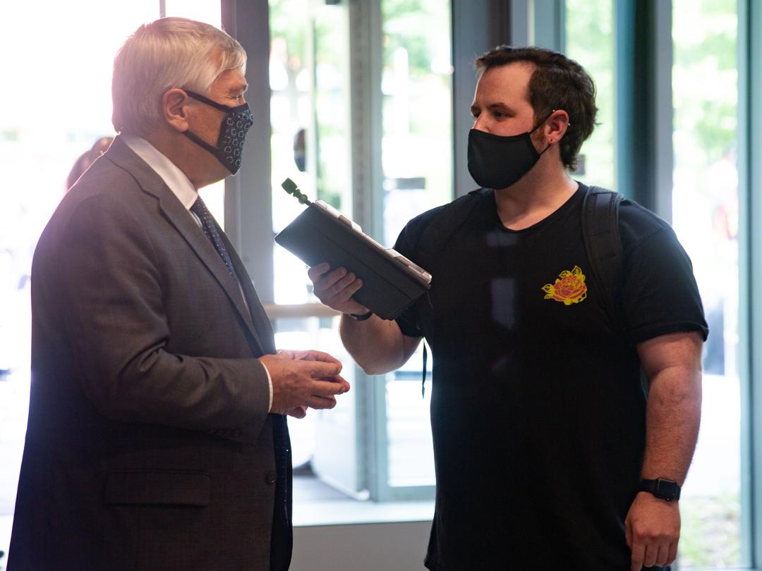 President Barron being interviewed by student holding a tablet. 
