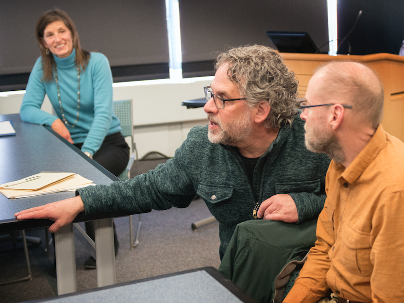 Male faculty member leans down to interact with older student in class.