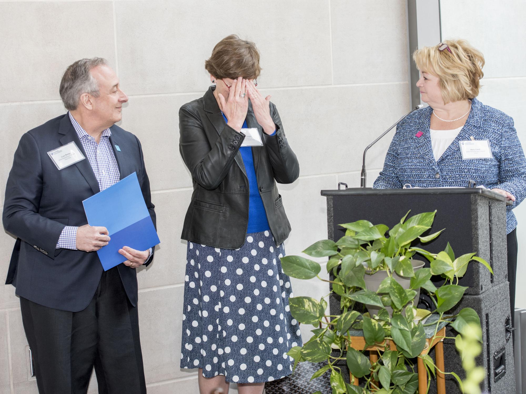Nan Crouter covers her face with her hands after learning of the endowment in her honor