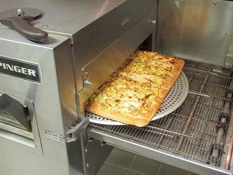 Breakfast pizza coming out of oven