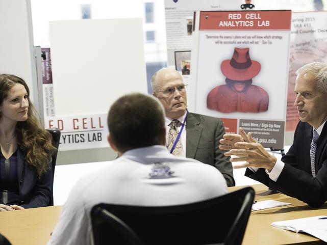 man speaks to others at a conference room table