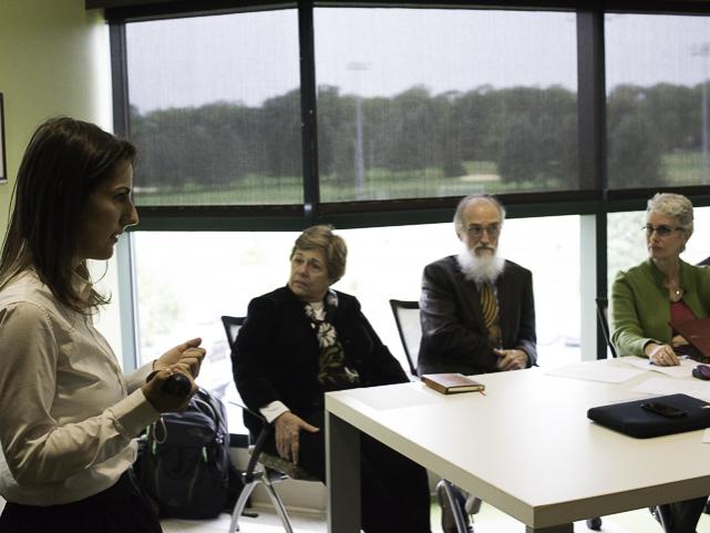 woman talks to group of people in a conference room