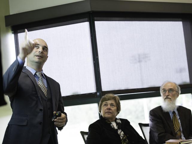 man points at presentation screen while others watch