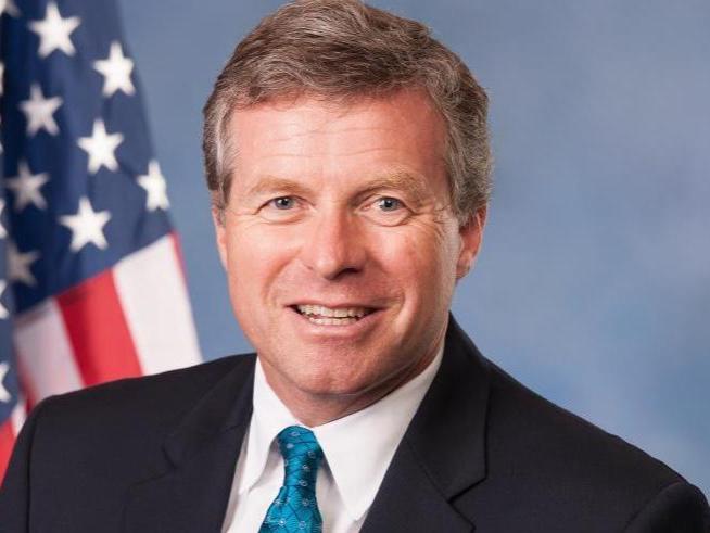 head shot of man in front of american flag