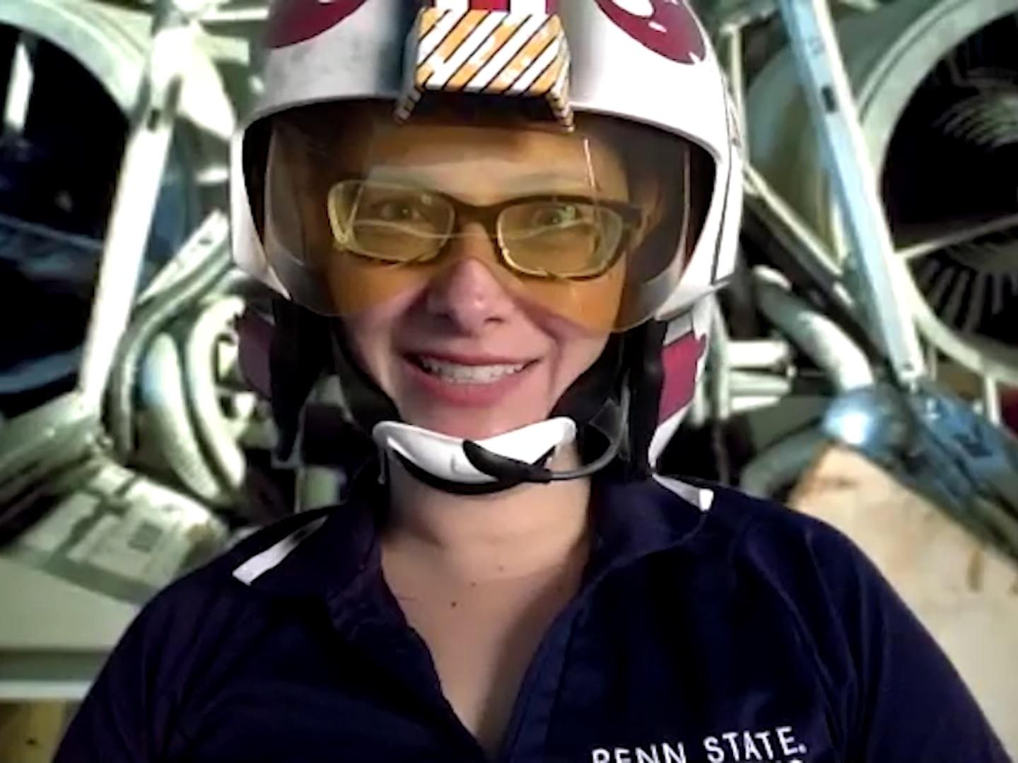 Penn State Behrend professor Charlotte de Vries wears a prop helmet while teaching in front of a spaceship-themed backdrop.