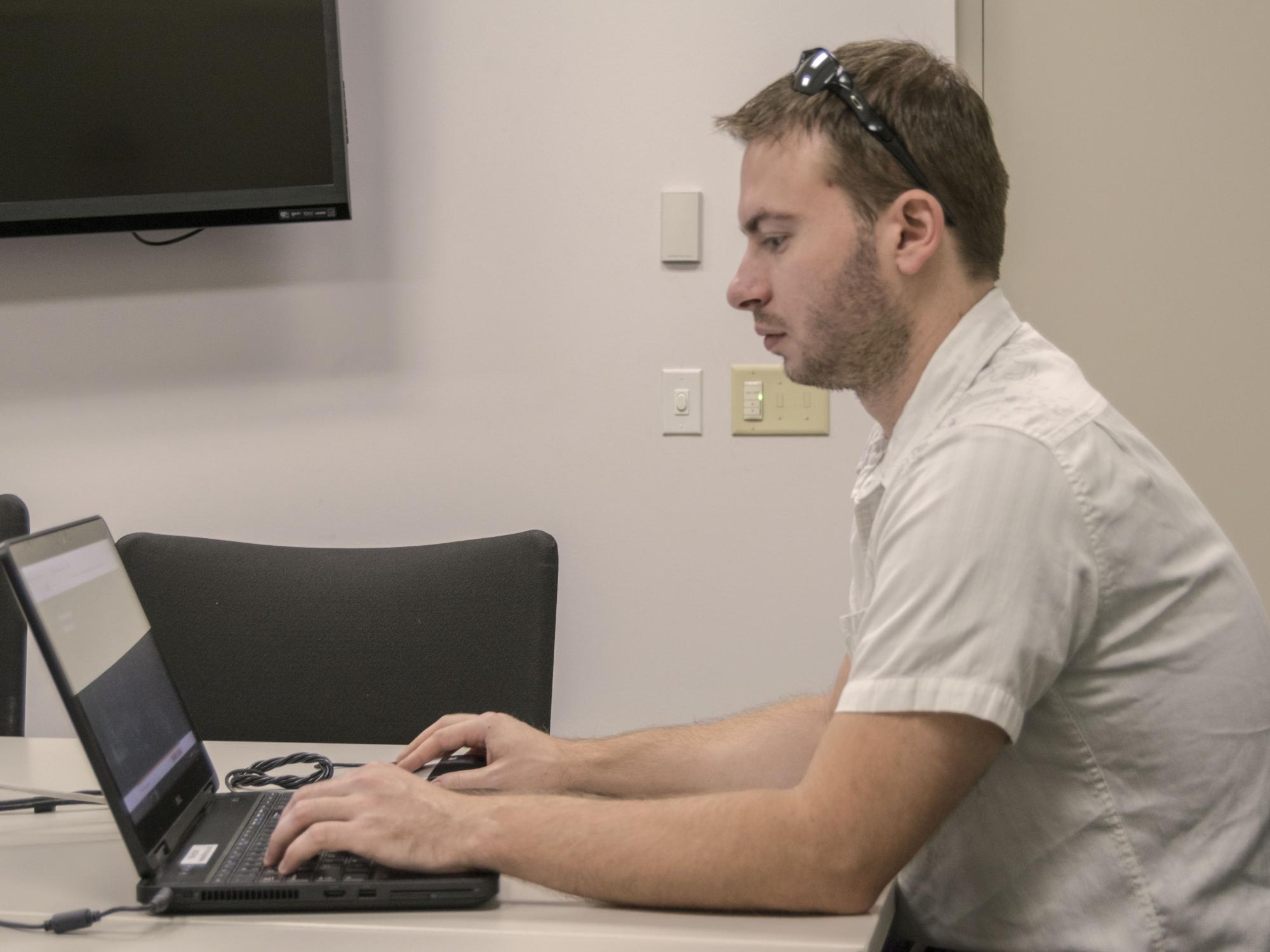 A side photo of Chris Masden sitting at his laptop.