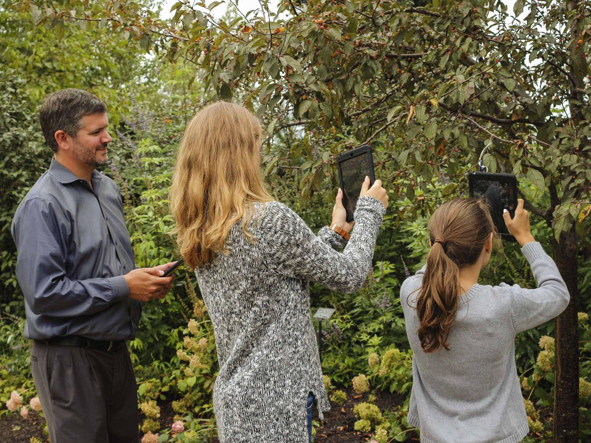 Chris Millet and children on iPads in The Arboretum