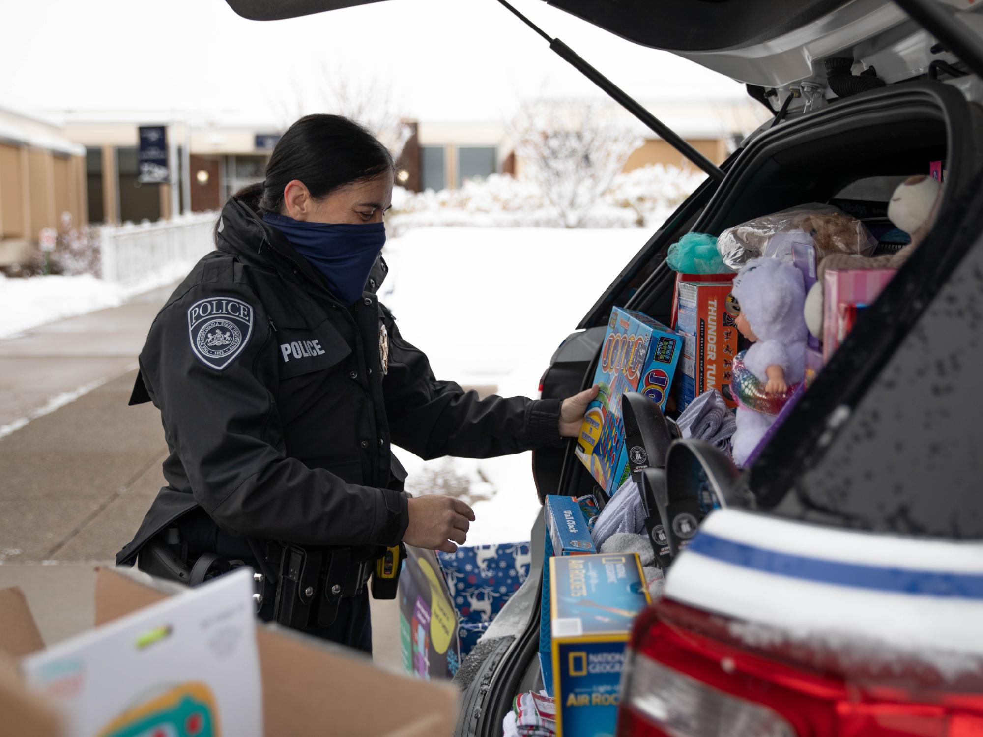 Police officer loading police cruiser with donated items