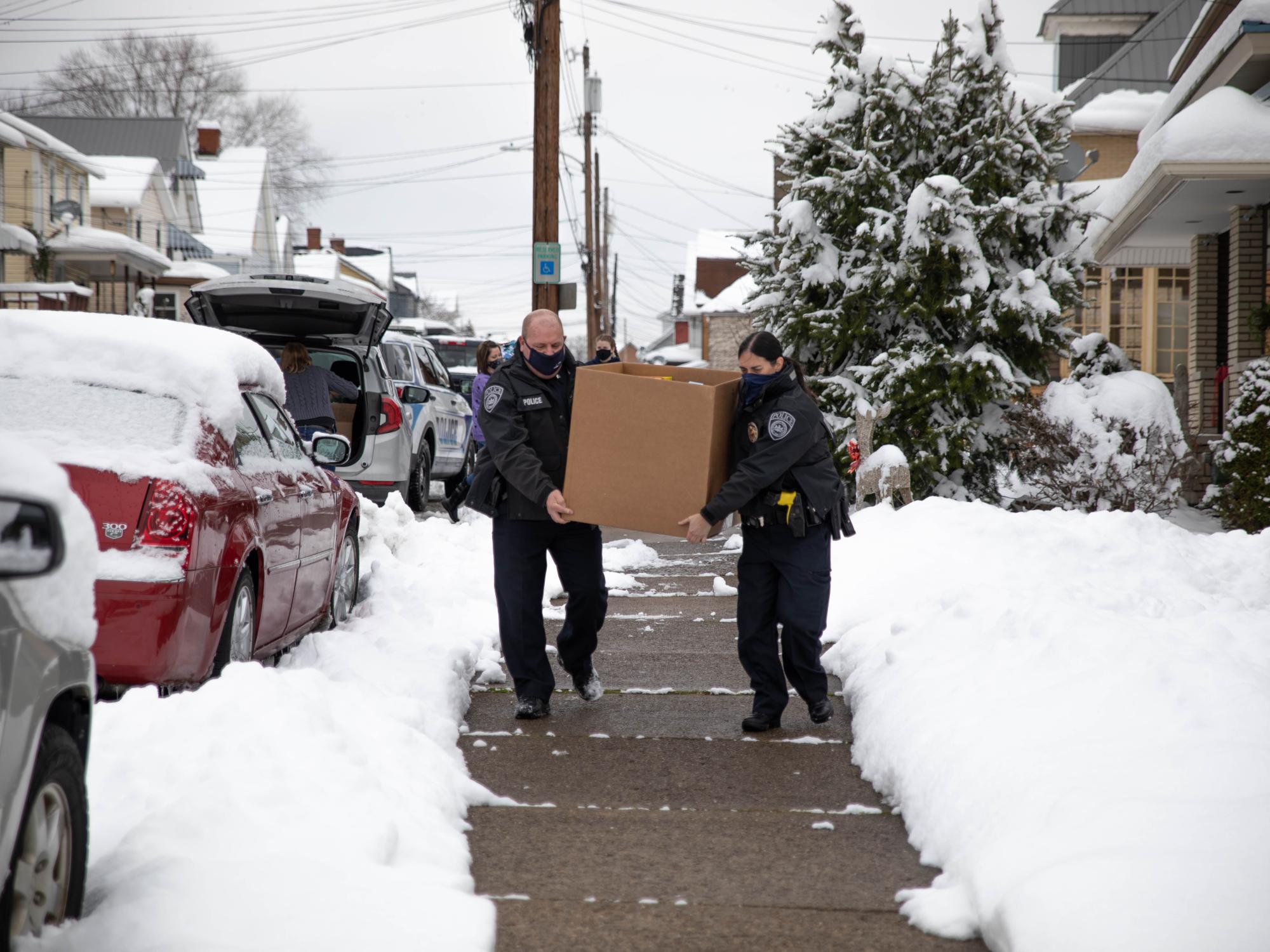 Two individuals carry box