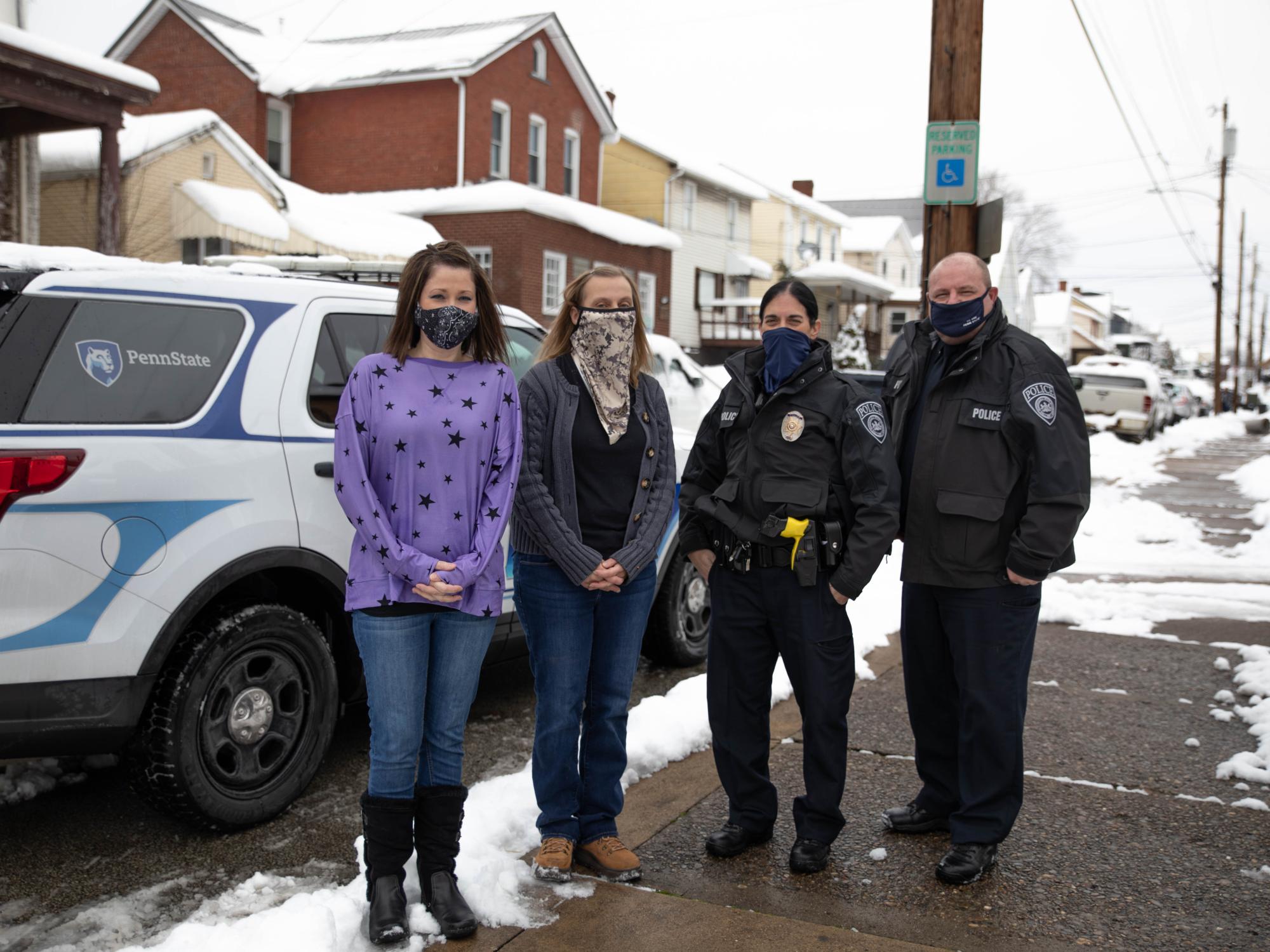 Four individuals stand outside wearing masks