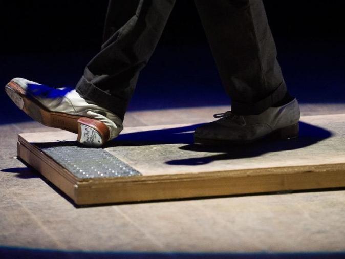 A dancer taps his shoes on an electrical trigger board with a metal strip at one end.