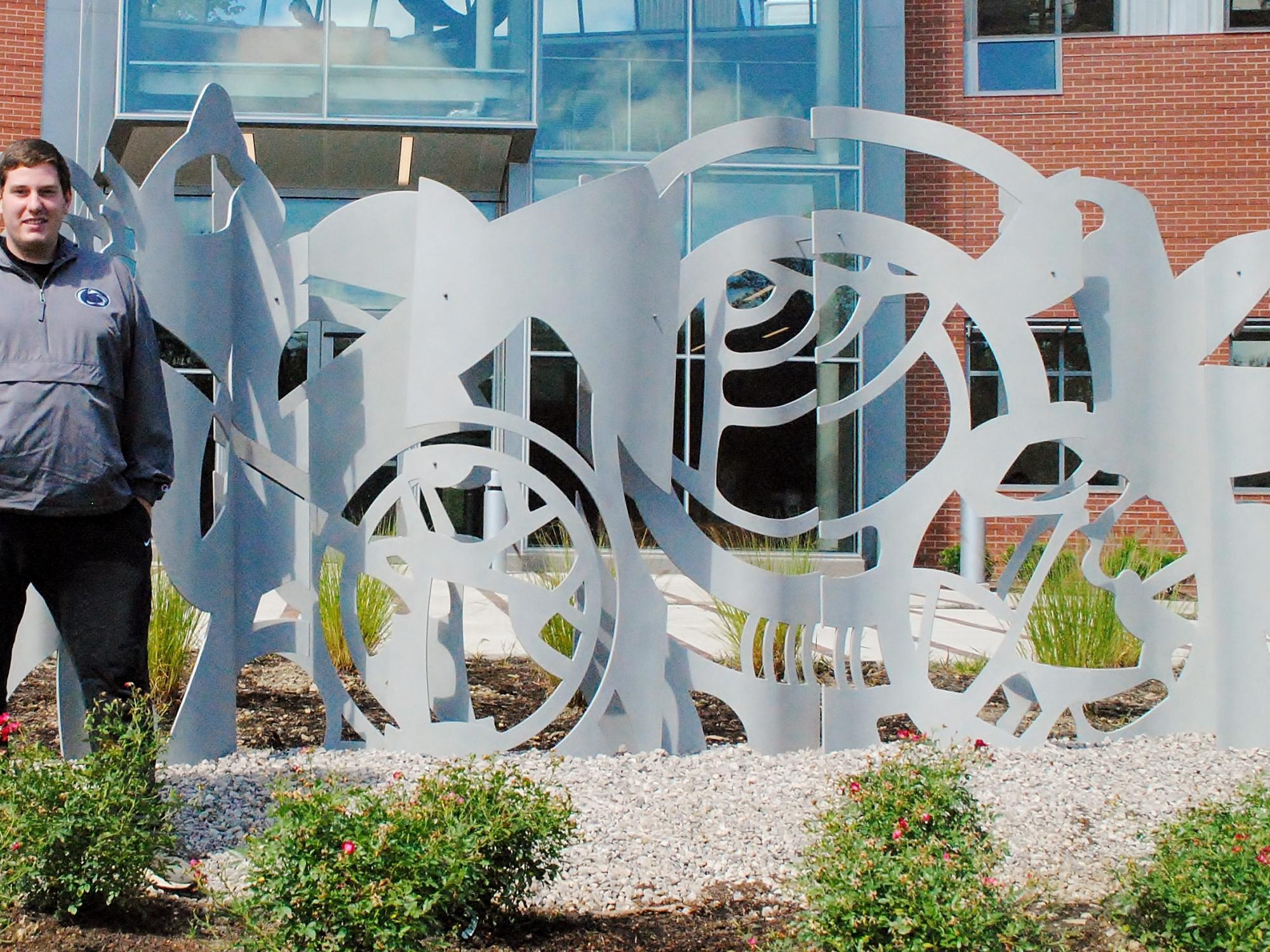 Penn State Behrend senior Will Gerould stands near a sculpture he worked on at the college's AMIC building.