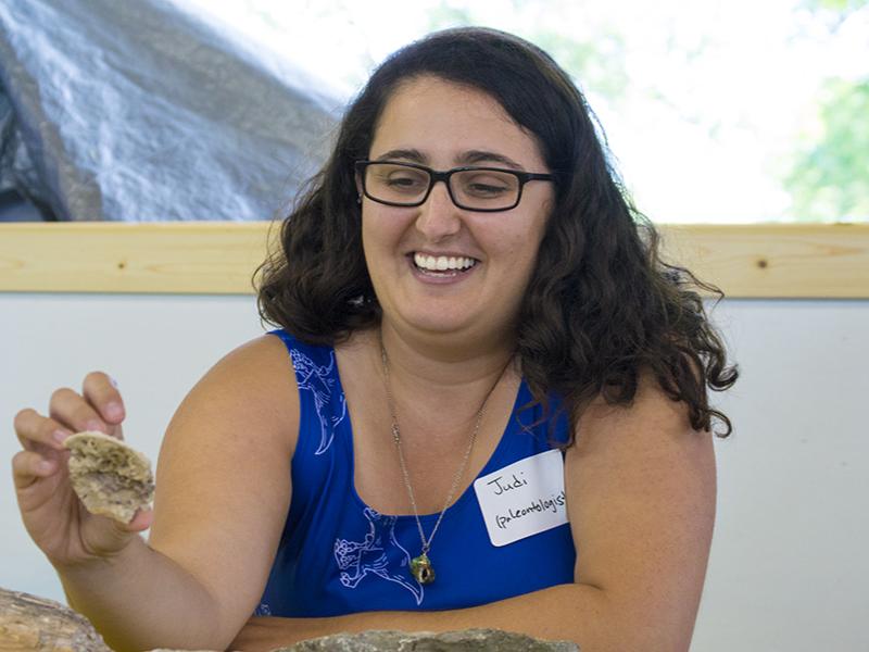Judi Sclafani, a Ph.D. candidate in geosciences, shows off a fossilized seashell that was invaded by corals and worm tubes. “Kids really like to see worms,” Sclafani said. “They either think it’s gross or really cool.”