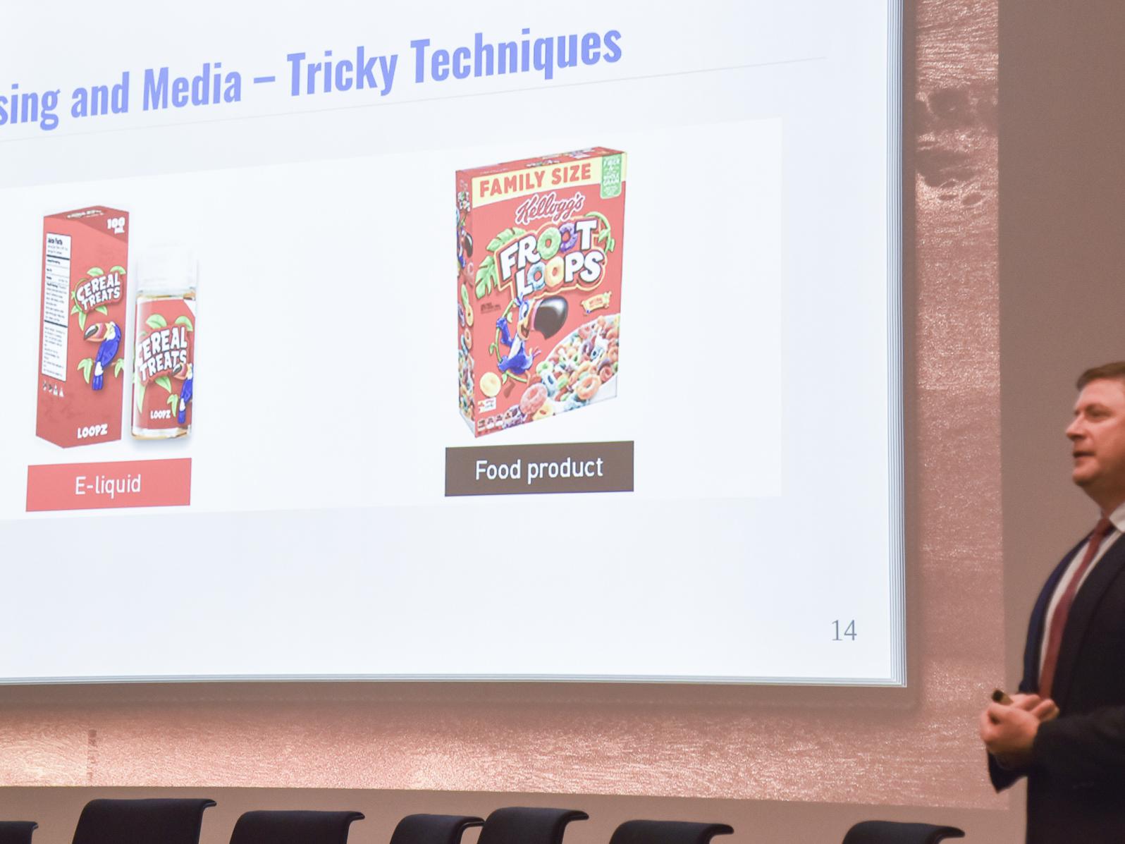 Craig Zettle describing a slide that notes similarities between an e-liquid box and a box of a popular cereal