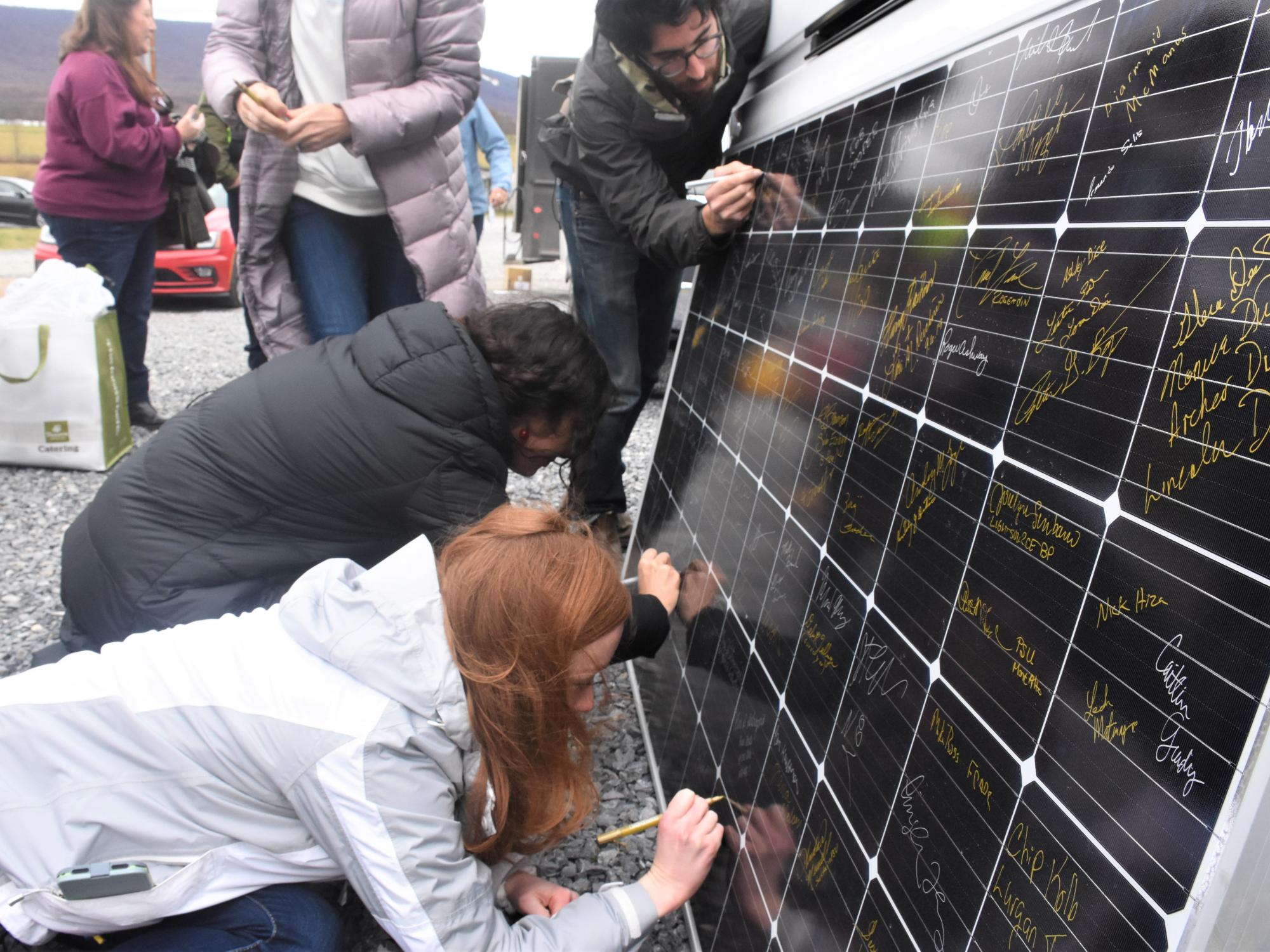 Penn State graduate students sign a solar panel.
