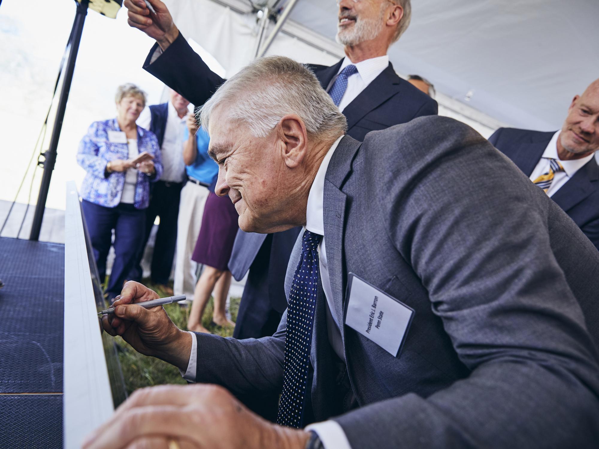 Penn State President Eric J. Barron signs a solar panel at the groundbreaking for a utility-scale solar project in Franklin County on Sept. 6, 2019.