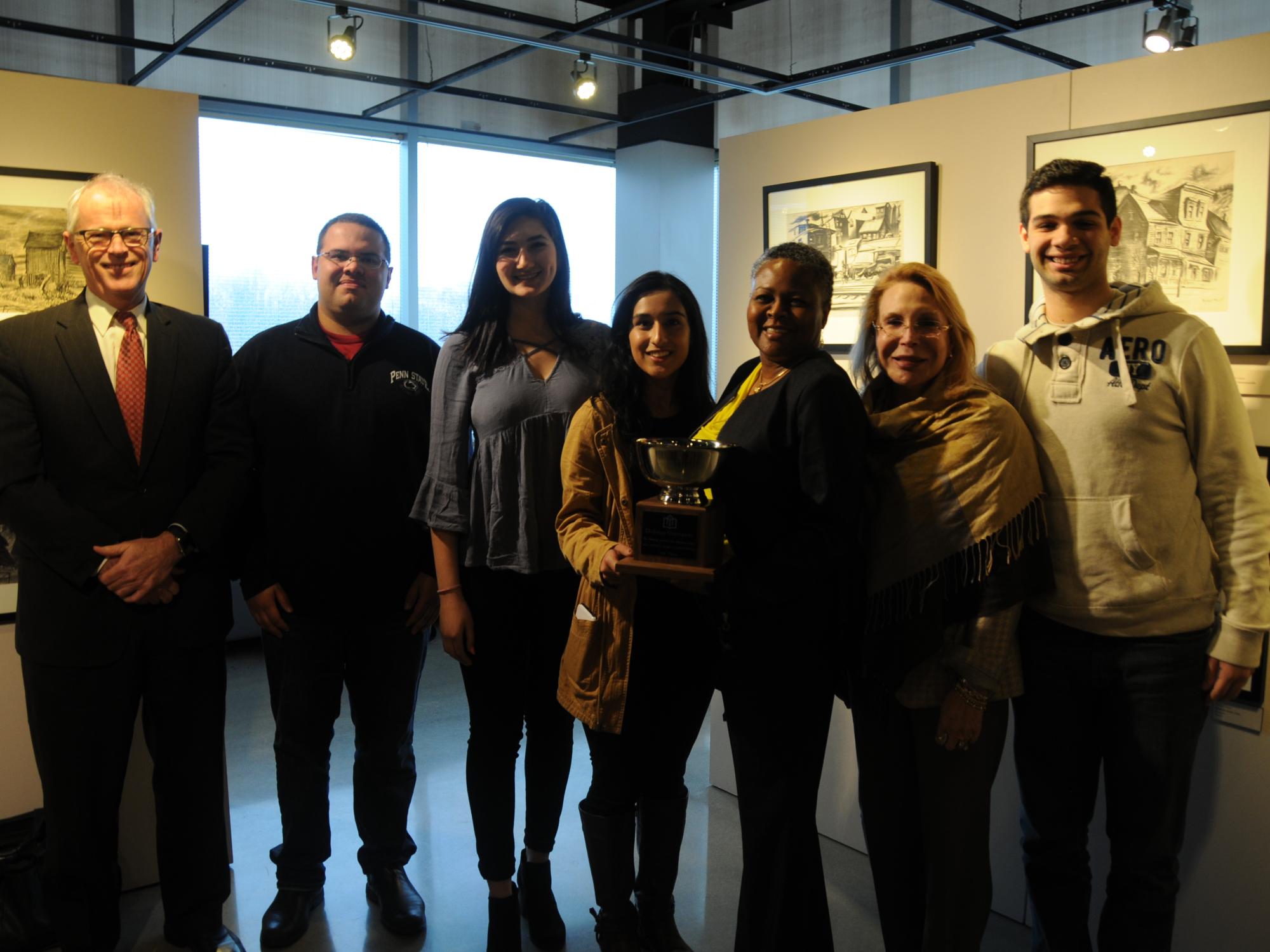 Winning debate team presented trophy to Dr. Richardson and posed in art gallery for group photo
