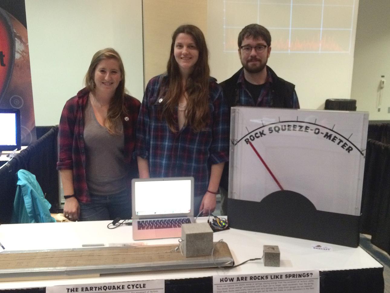 three students standing next to demonstration table