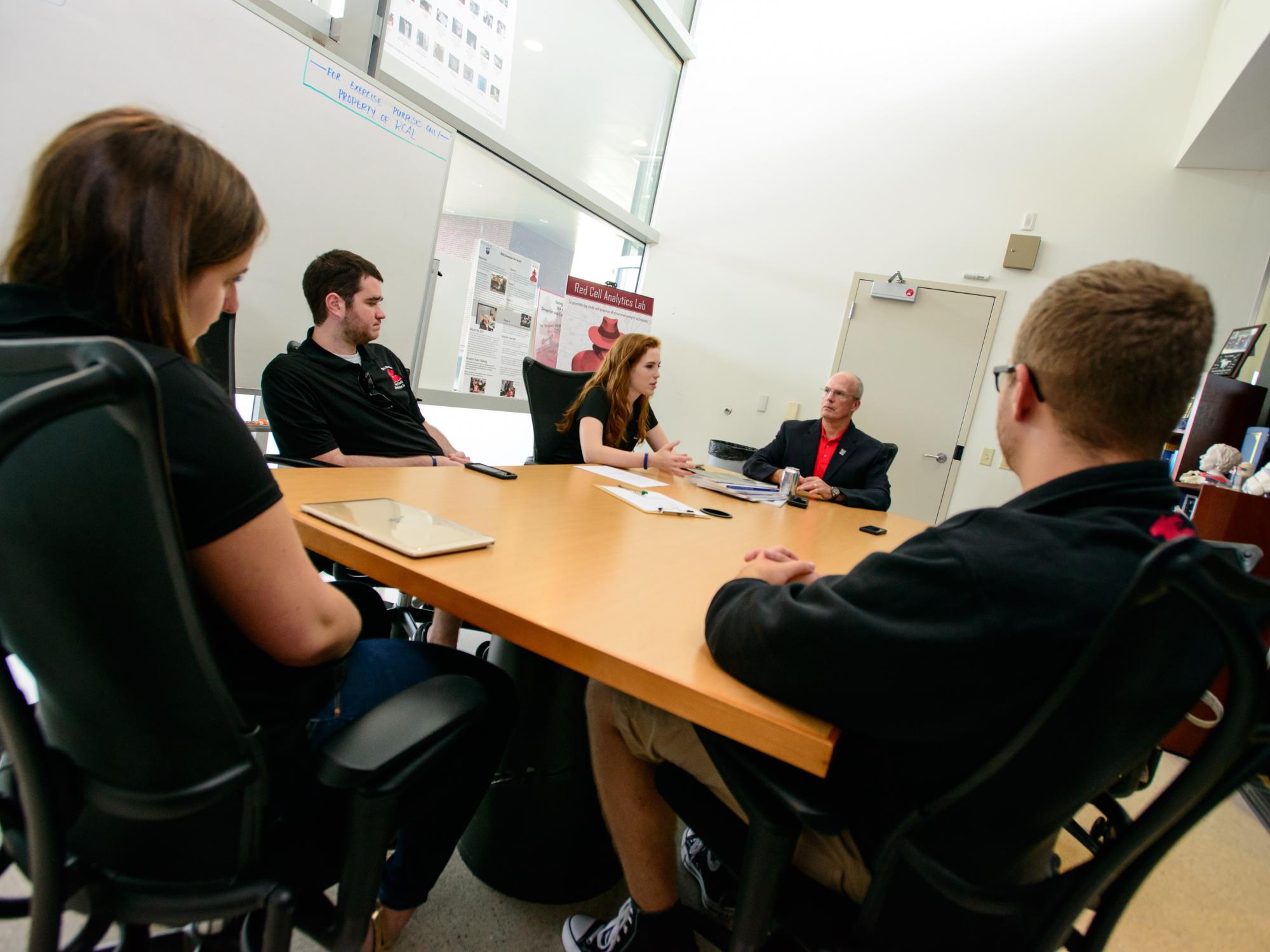Students sit around a table with lab director Jake Graham