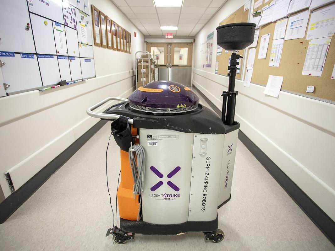 A Xenex robot cleans a hallway at Hershey Medical Center. It looks like a large trash can with a lid can on wheels.