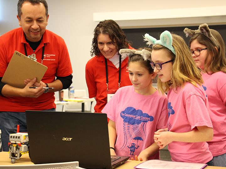 Professors Flavio Cabrera and Dr. Marietta Scanlon listen to a team's presentation on their robot's programming