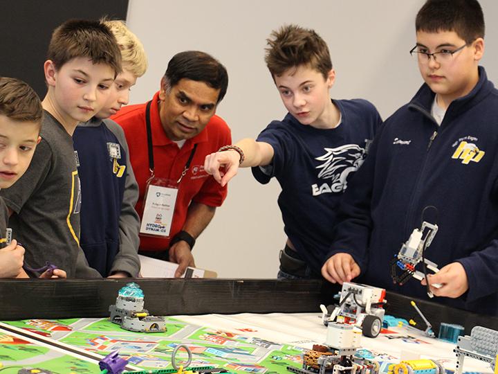 Dr. Rungun Nathan listens to a team's explanation of their robot's programming
