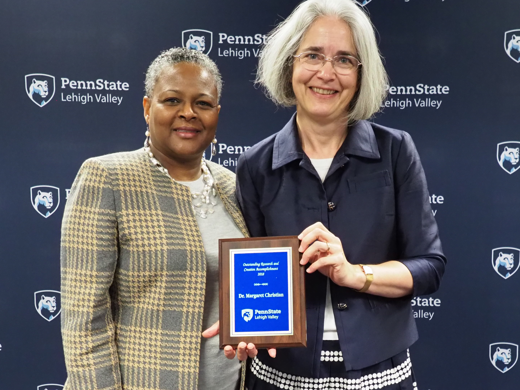 a woman handing a professor a plaque