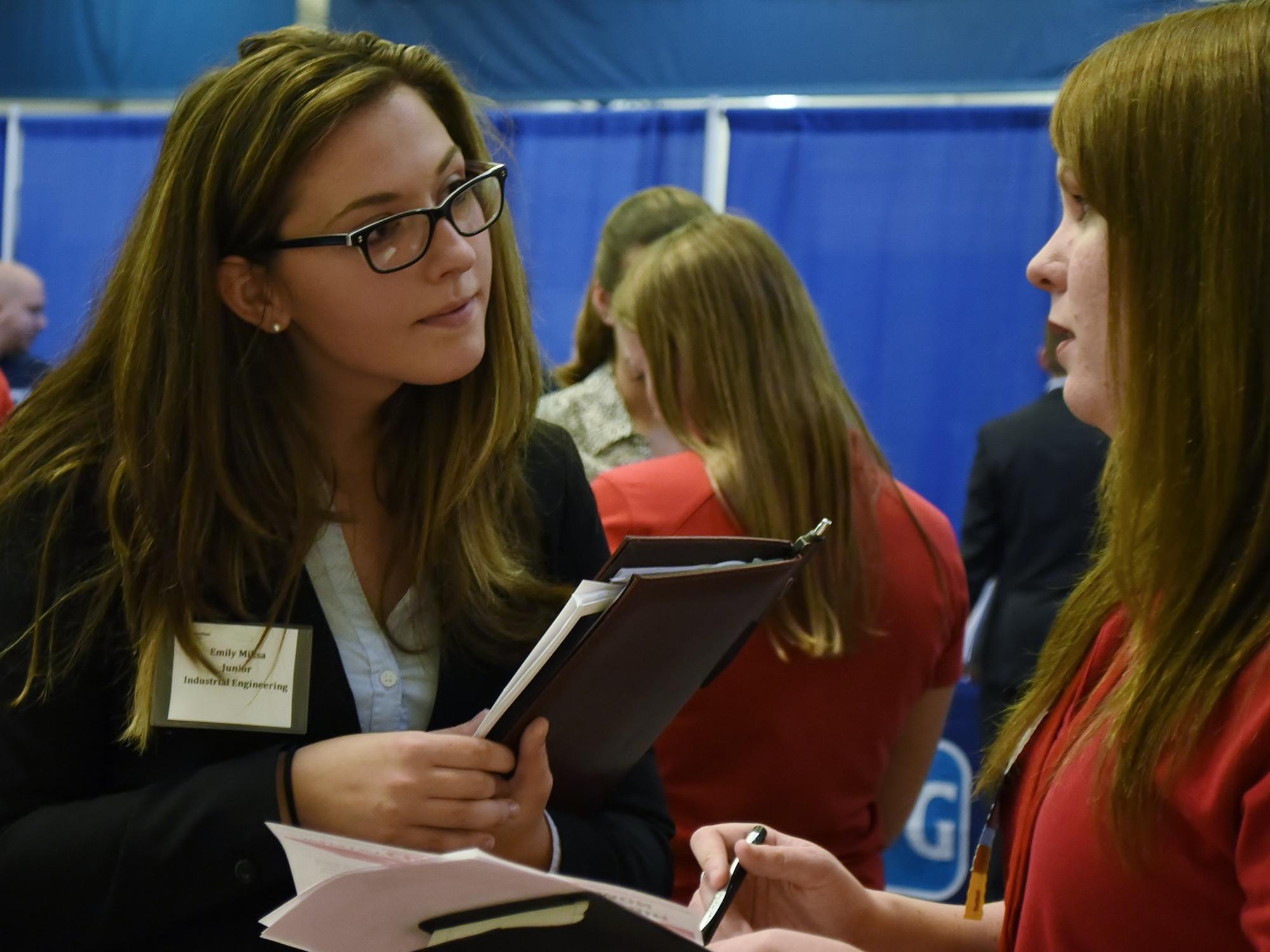 Female student talking to recruiter at job fair.