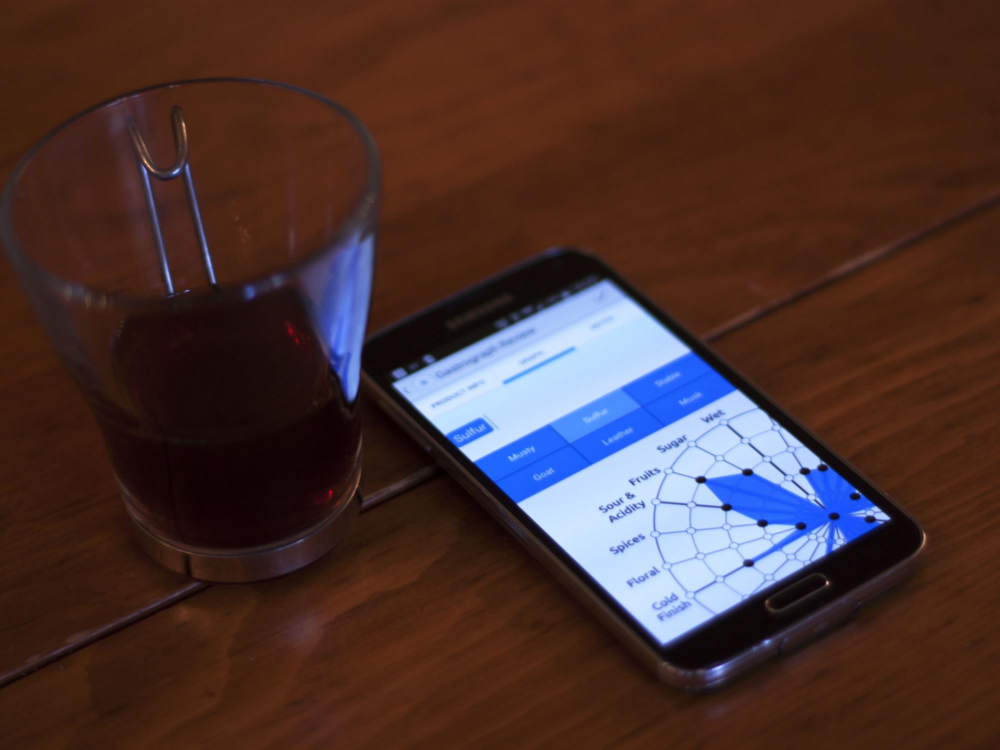Smartphone with mobile app open lays next to glass of coffee