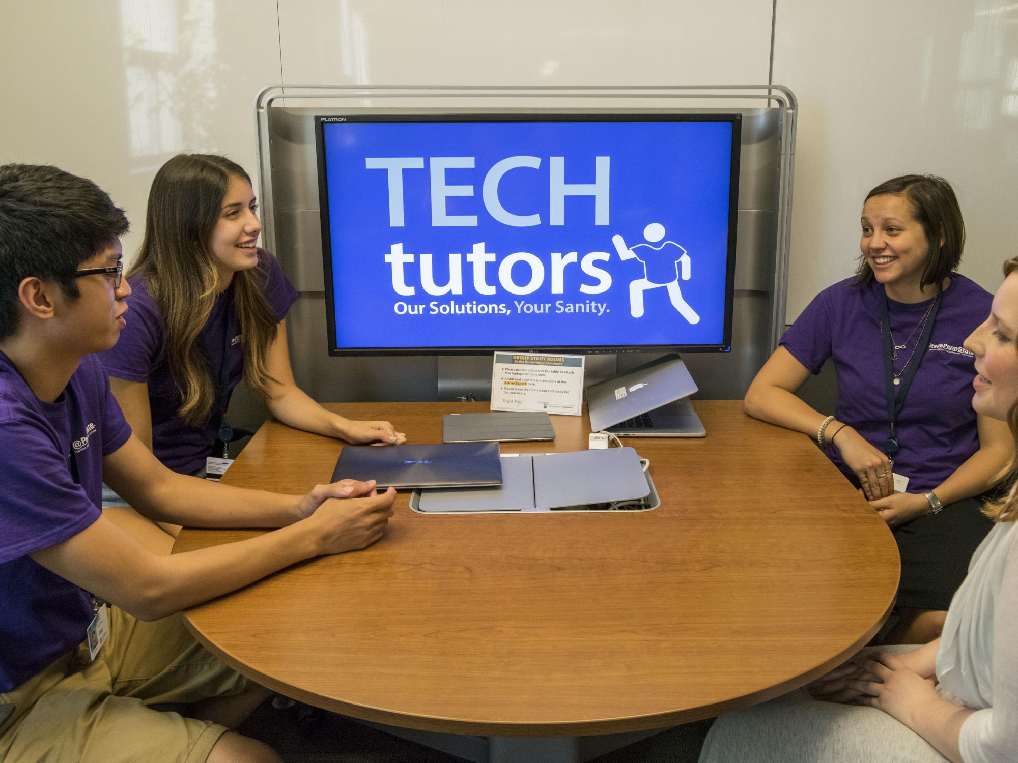 Three tech tutors and a staff member sit around a table talking