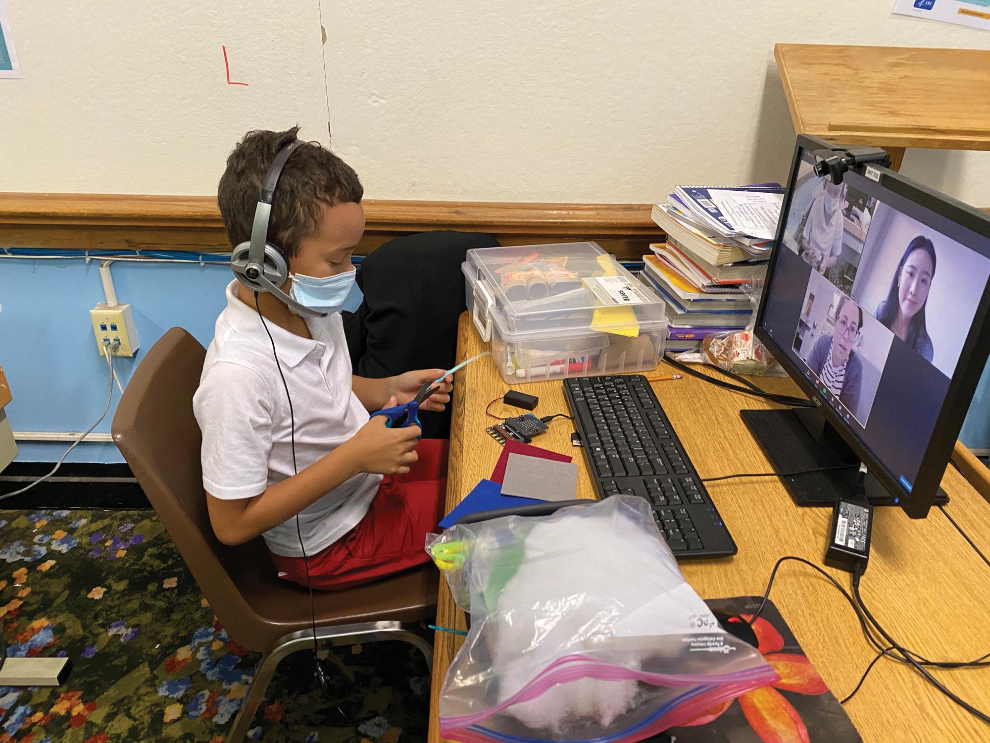 An elementary student works on a science experiment with his pre-service teacher from Penn State via Zoom.