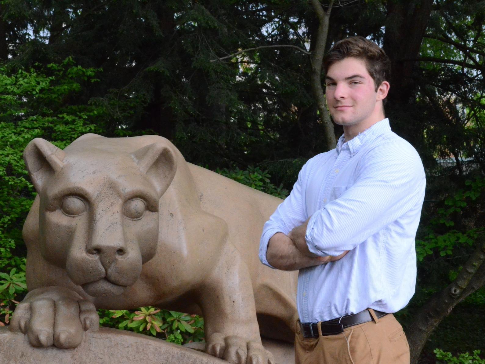 Young man poses for camera next to lion statue