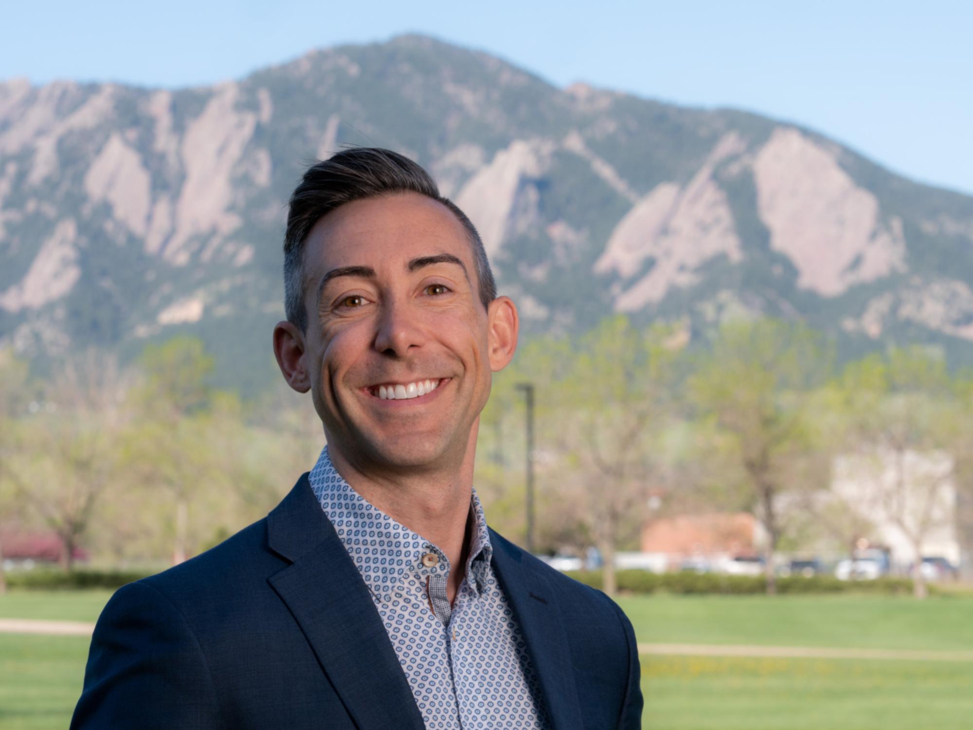 picture of man smiling for camera in front of mountains