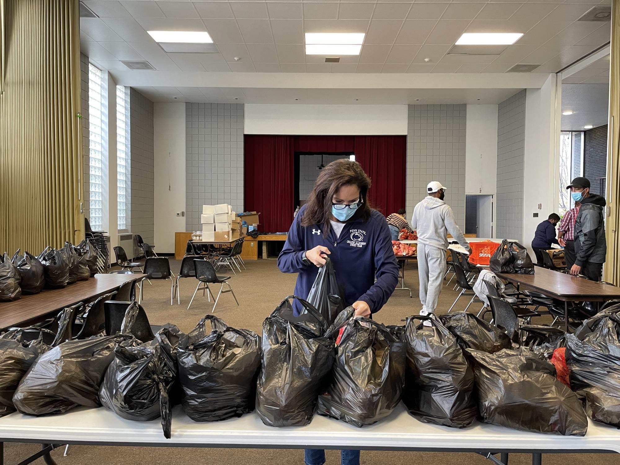 Woman placing a plastic bag on a table filled with other plastic bags.