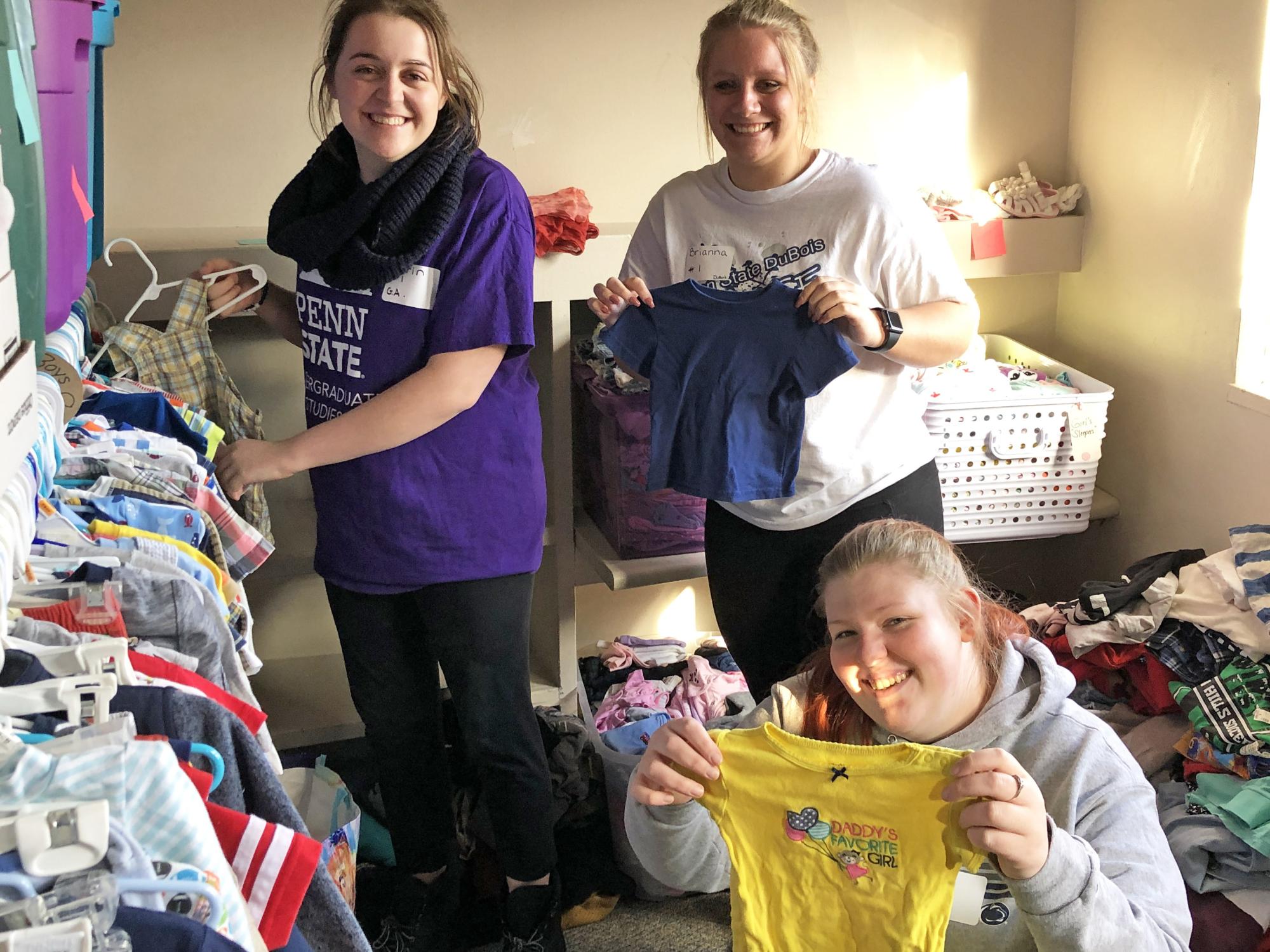 Three students holding up clothing 