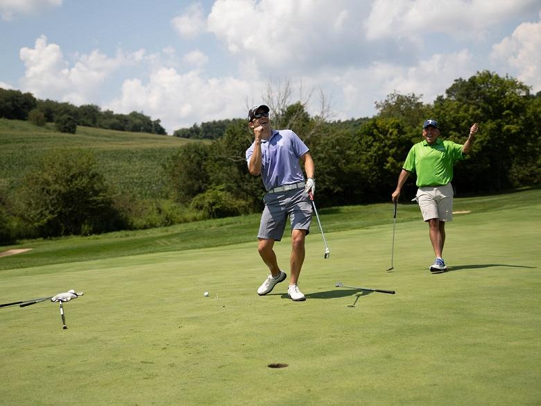 Two golfers celebrate putt on golf course
