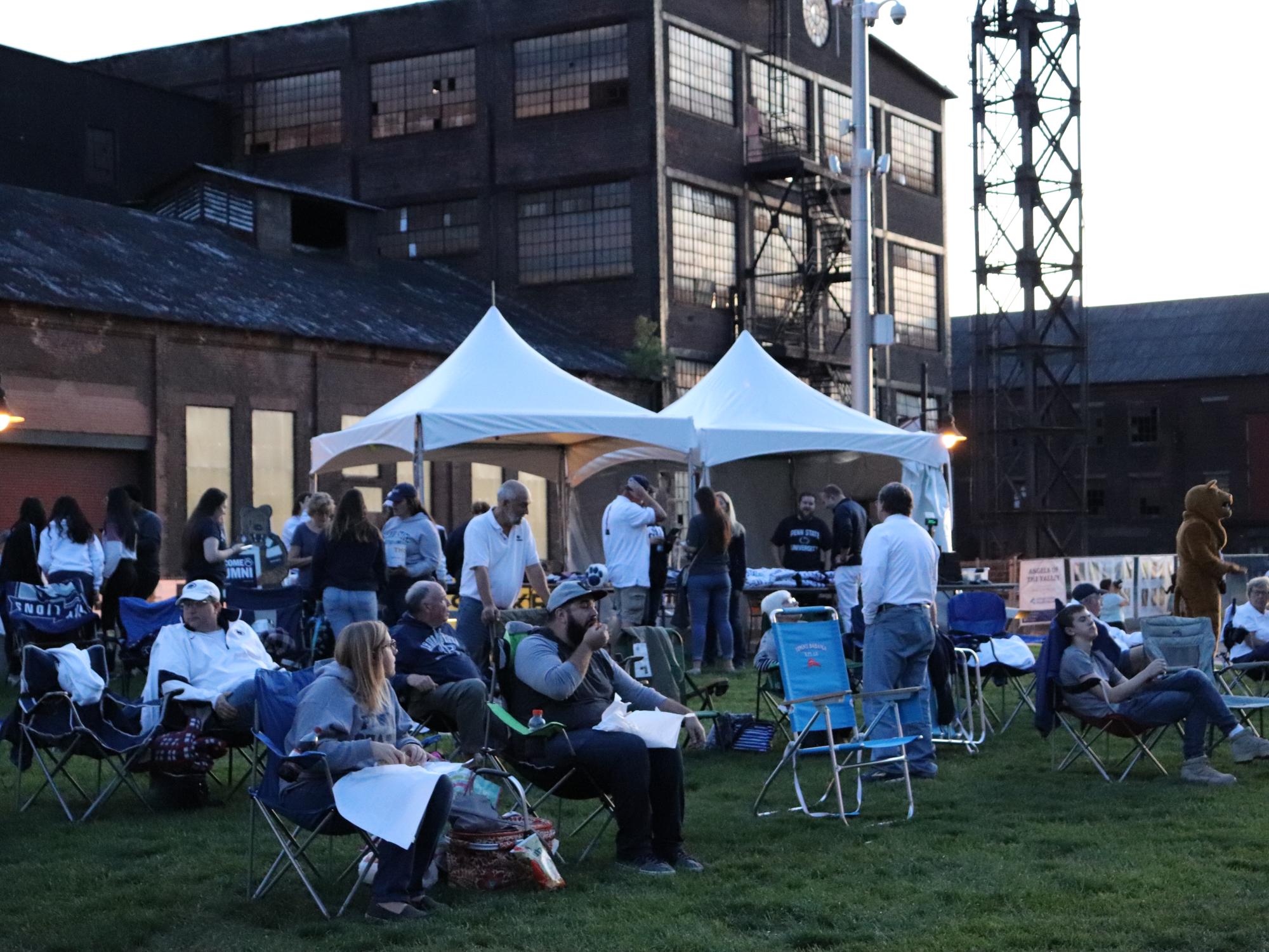 group of people sitting on lawn ready to watch big screen