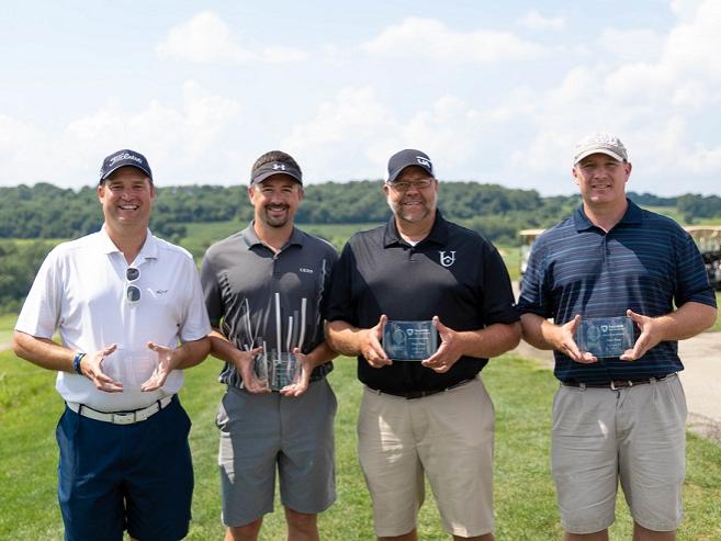 Four golfers holding trophies