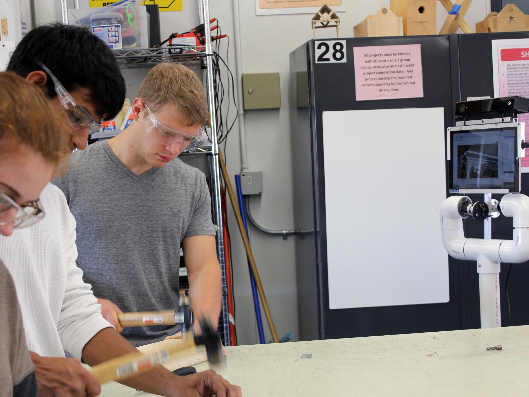 Penn State engineering students working while co-robot Pennie learns from their actions.
