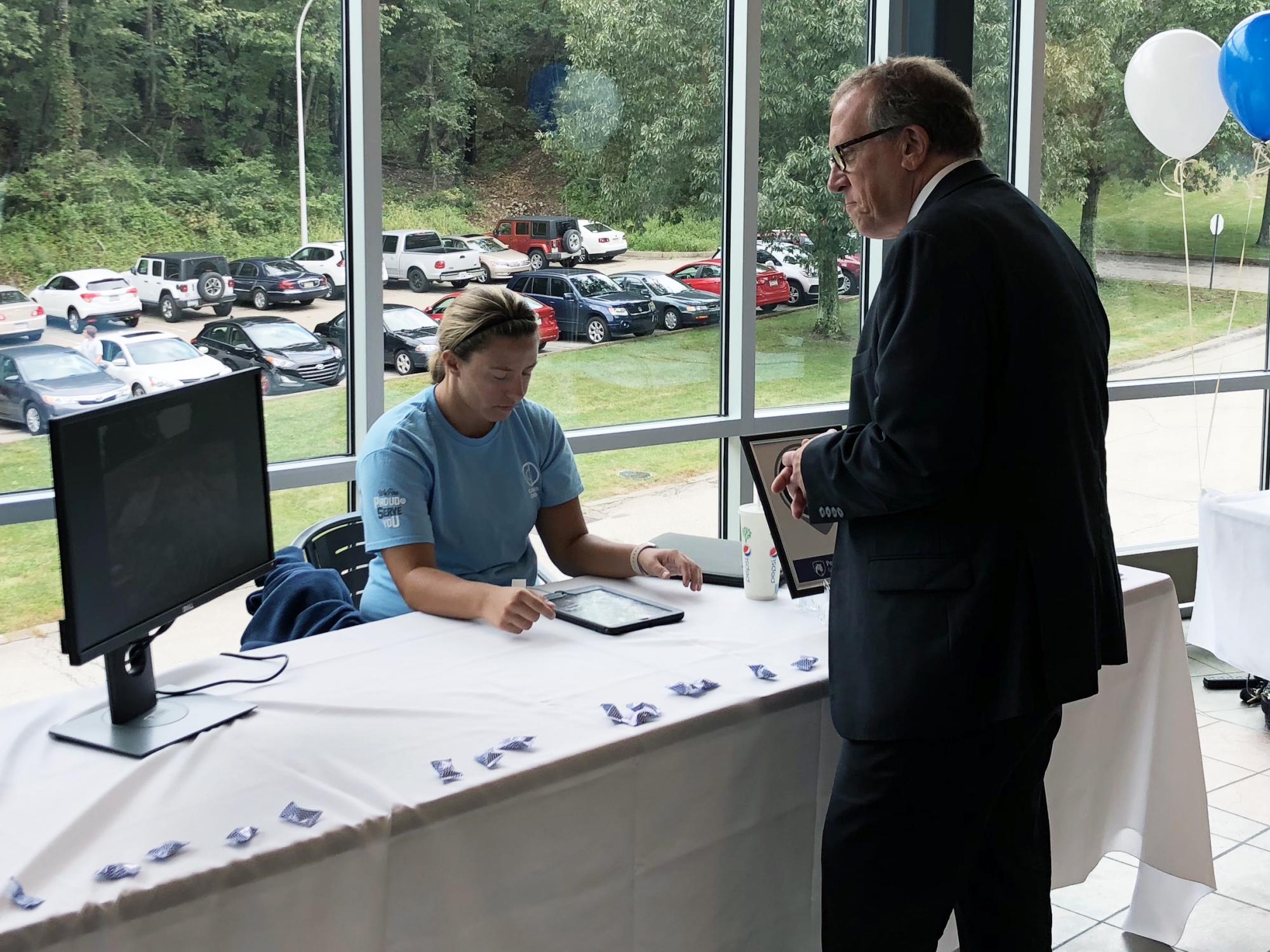 Student showing Vice President of Information Technology Michael Kubit how Physical plant is using iPad. 