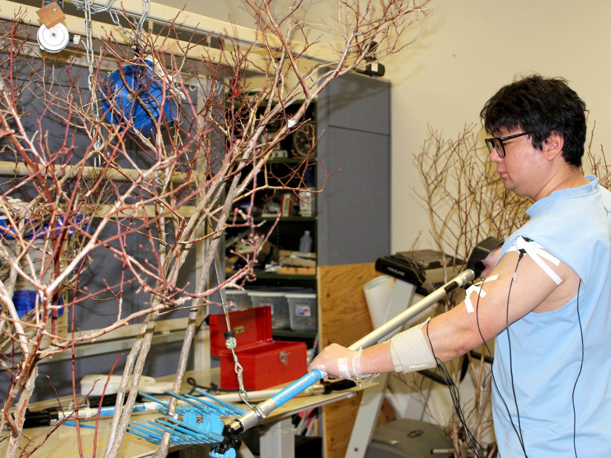 Graduate student Eunsik Kim tests a modified olive shaker while hooked up to an electromyogram to measure the stress on his muscles.