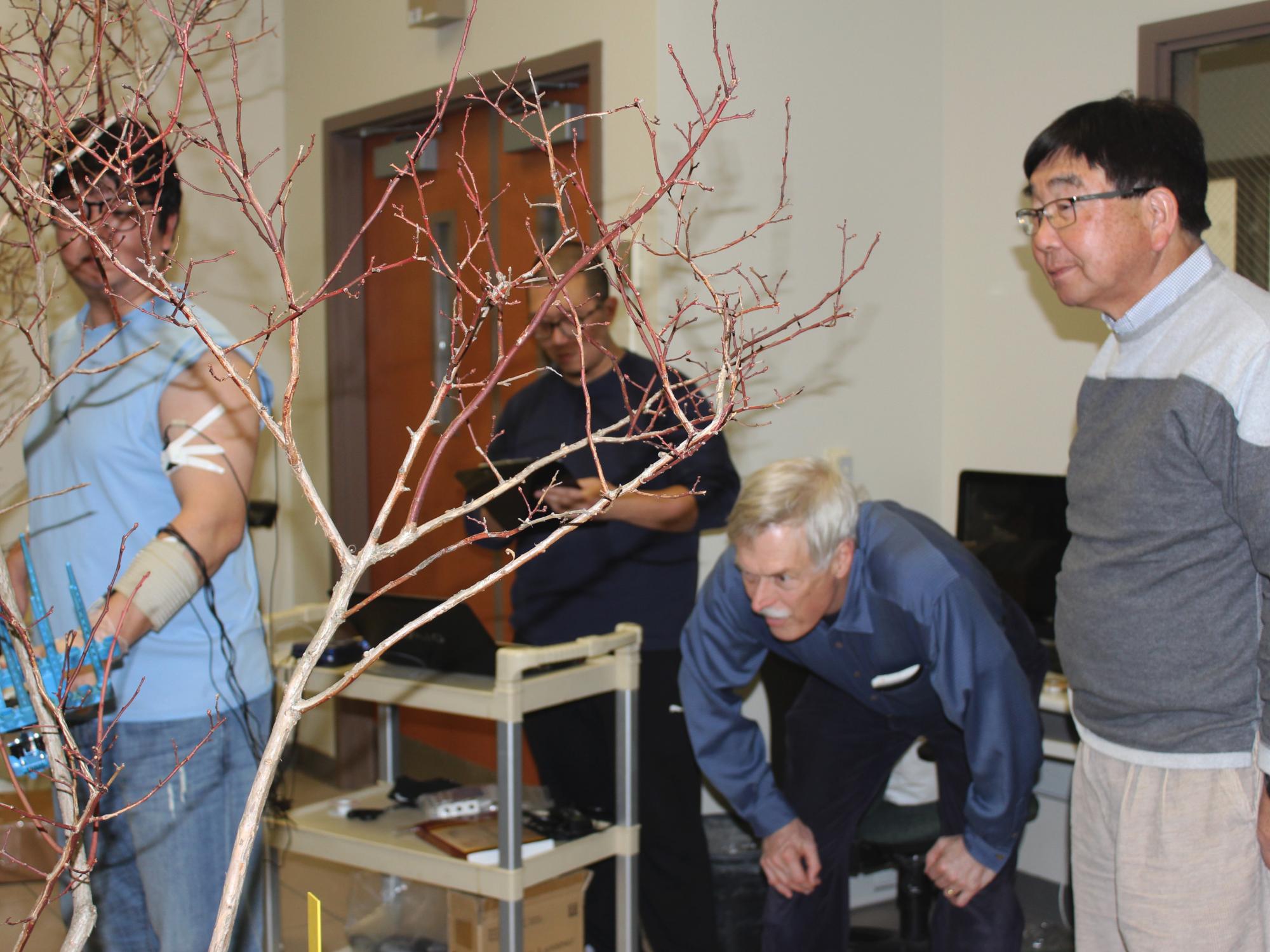 Kim uses one of the shakers on the blueberry bush while fellow graduate student Kiseok Sung records the force the shaker has on Kim’s muscles as Andris Frievalds and Fumioni Takeda observe the test.