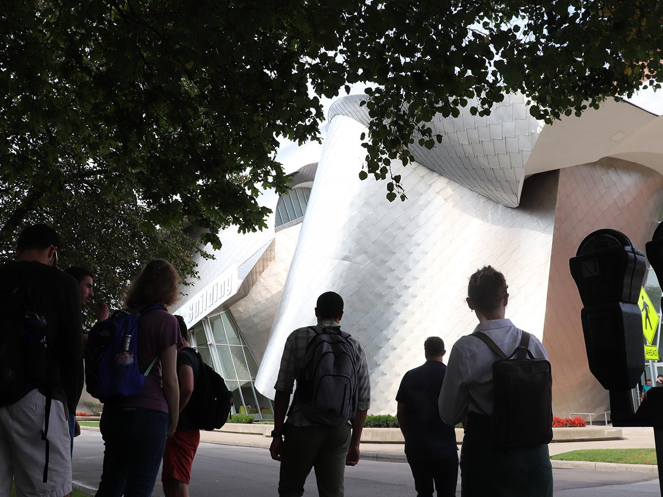 The backs of students as they observe Lewis Building at Case Western Reserve University.