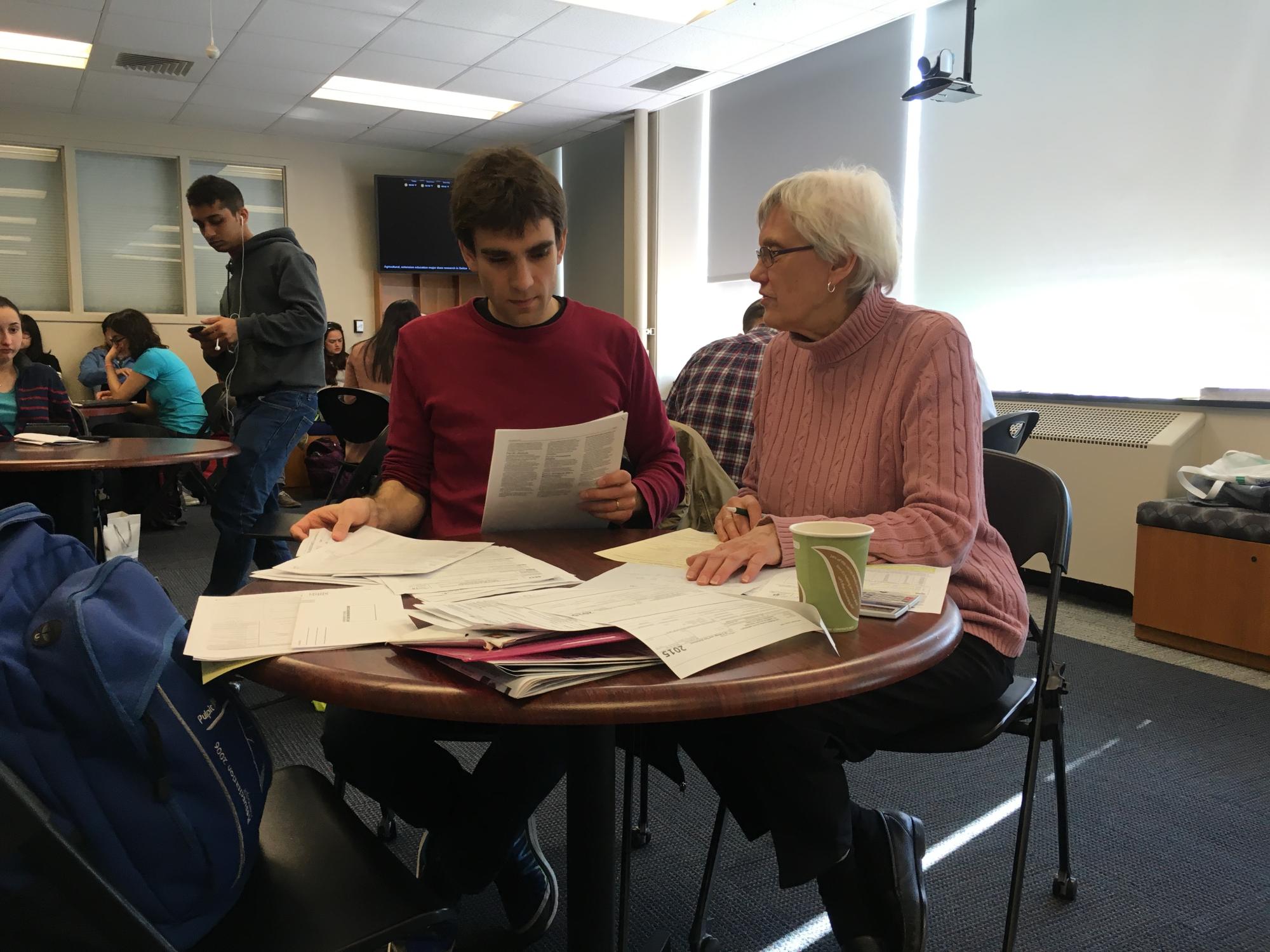 An American woman helping a male international student with taxes