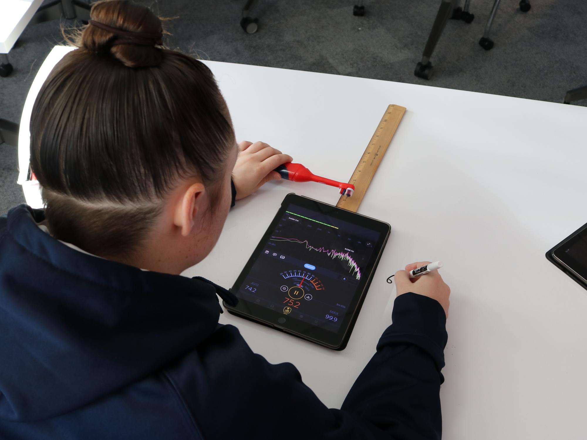 girl holding electric toothbrush near ipad 