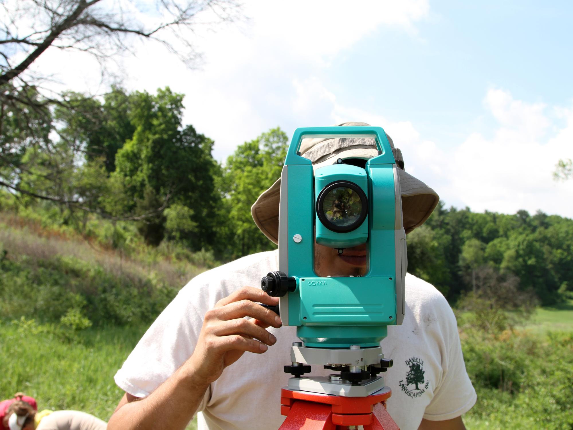 A field school participant looks through the lens of the total station. 
