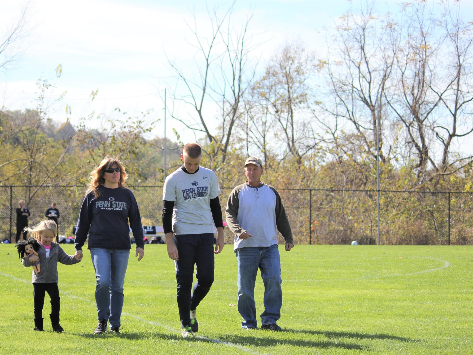 Four people walk across soccer field