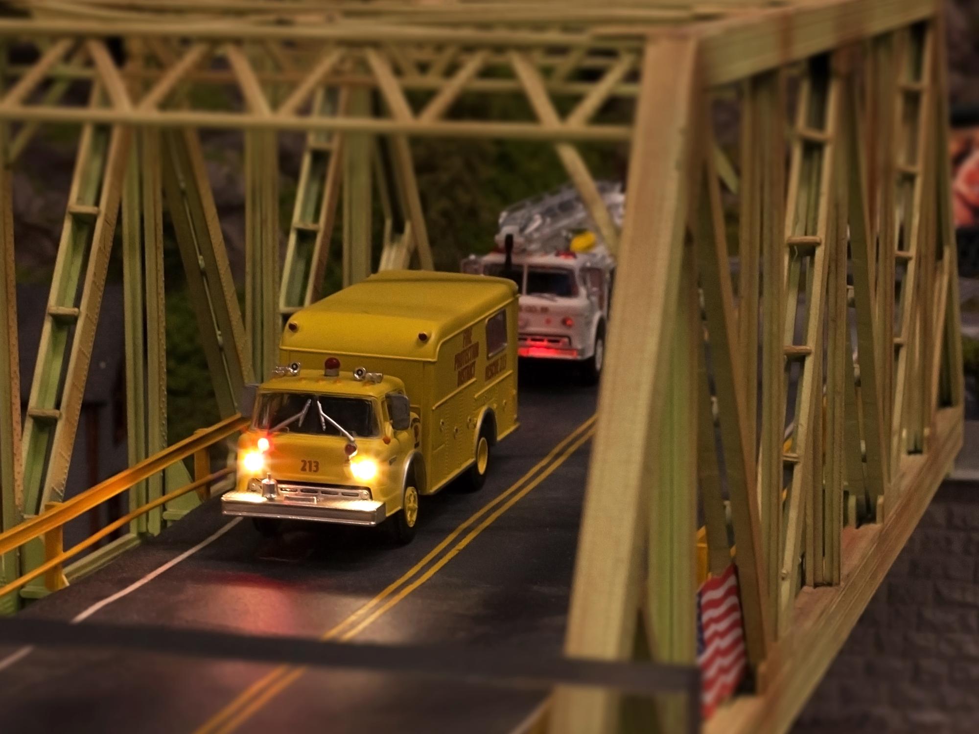 A miniature truck with working headlights crosses a bridge 